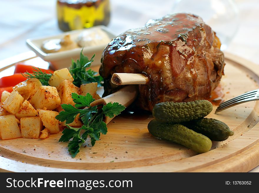 Pork with vegetables on a wooden support with sauce and mustard