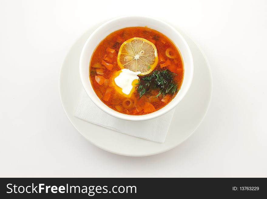 Soup with lemon and olives in a white plate on a white background