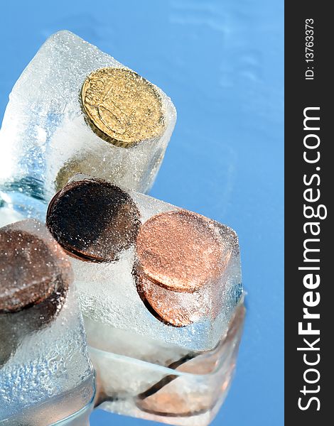 Coins inside ice cubes isolated on blue background. Coins inside ice cubes isolated on blue background