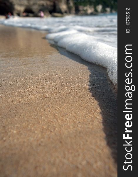 The ocean wave leaves on a sandy beach