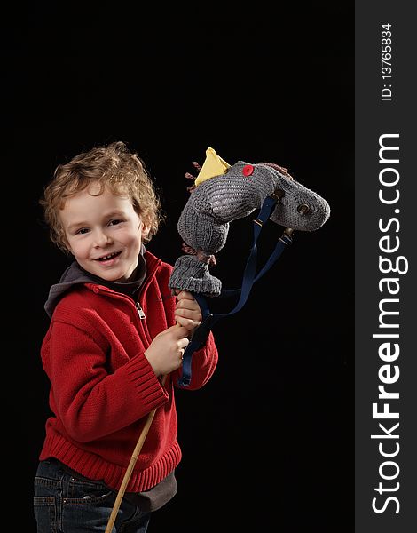 Young white boy playing with horse made of a sock on black background. Young white boy playing with horse made of a sock on black background