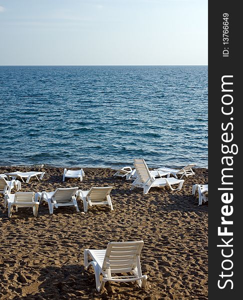 Many chaise lounges on beach under evening sun