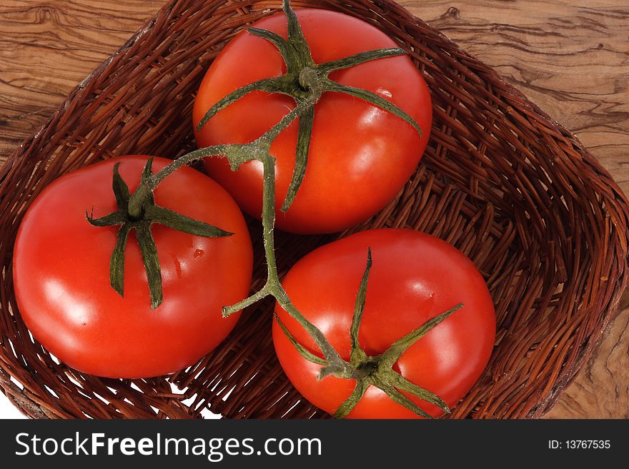 Three fresh red tomato on woven plate