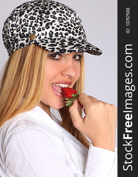 Beautiful young blonde woman eating strawberry, wearing hat with leopard-look. Beautiful young blonde woman eating strawberry, wearing hat with leopard-look