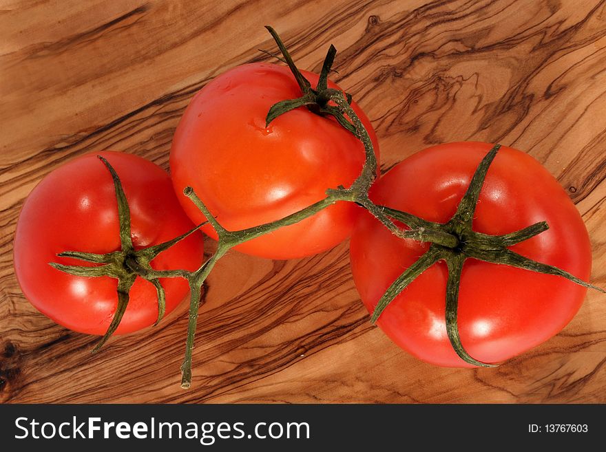 Three fresh red tomato on brown background