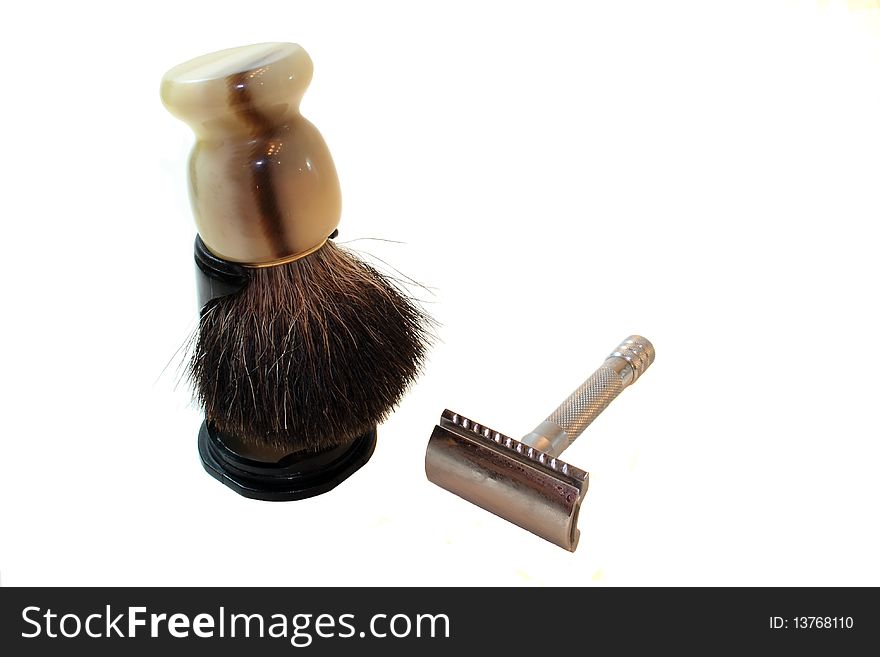 An old fashioned safety razor and shaving brush isolated on white. An old fashioned safety razor and shaving brush isolated on white.