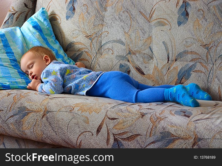 The sleeping small, beautiful boy laying on a sofa with an open mouth. The sleeping small, beautiful boy laying on a sofa with an open mouth