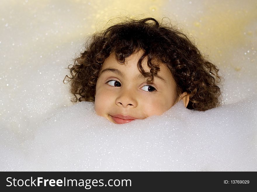 A small girl in a bubble bath filled with soap foam. A small girl in a bubble bath filled with soap foam