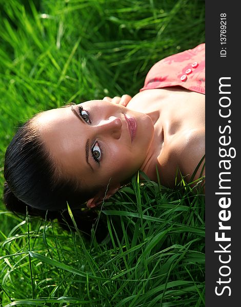 Girl is laying down on a meadow and relax in the green grass. Nice portrait. Girl is laying down on a meadow and relax in the green grass. Nice portrait