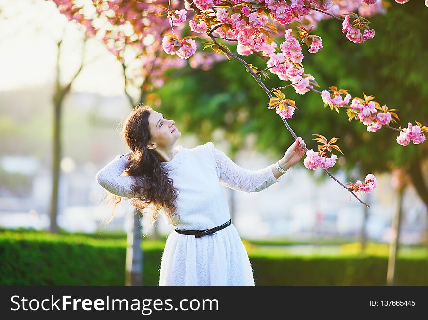 Happy young woman in white dress enjoying cherry blossom season in Paris, France. Happy young woman in white dress enjoying cherry blossom season in Paris, France