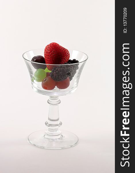 Fresh fruit in a clear crystal glass isolated on white background.