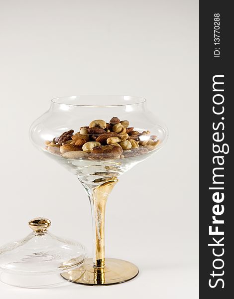 Mixed nuts in a clear crystal bowl on a white background. Mixed nuts in a clear crystal bowl on a white background.