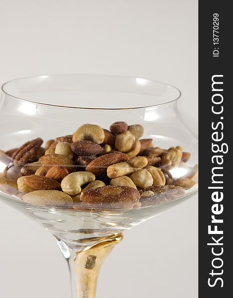Mixed nuts in a clear crystal bowl on a white background. Mixed nuts in a clear crystal bowl on a white background.
