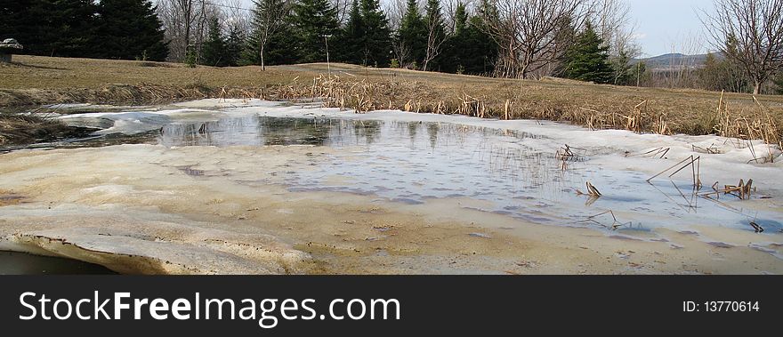 A pond is melting in spring, in rural Quebec. A pond is melting in spring, in rural Quebec