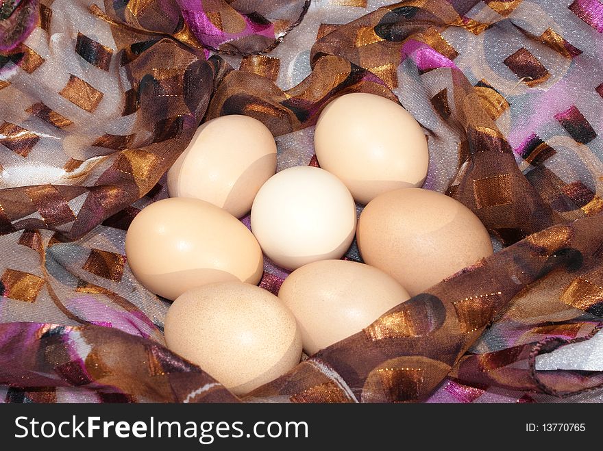 Chicken eggs in a nest made of colored handkerchief in the form of a ring. Chicken eggs in a nest made of colored handkerchief in the form of a ring