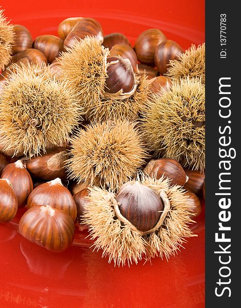 Sweet Chestnuts And Chestnut Husks On Red Plate