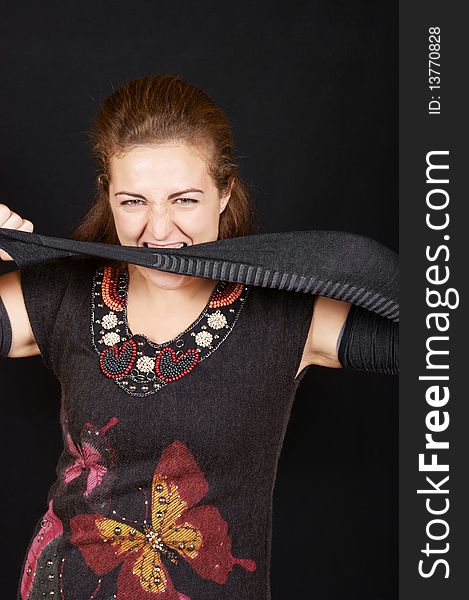 Portrait of a beautiful young woman wearing black dress and gantlets. She's stretching one gantlet and biting it. Studio shot over black background. Portrait of a beautiful young woman wearing black dress and gantlets. She's stretching one gantlet and biting it. Studio shot over black background.