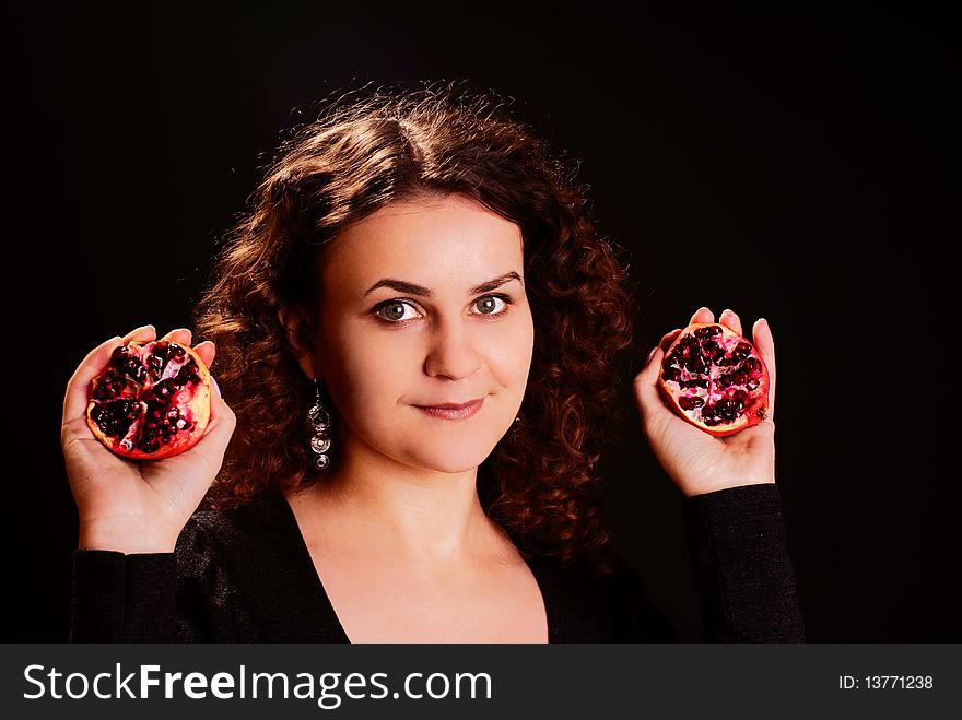 Portrait of a young beautiful woman with pomegranate. Studio shot.