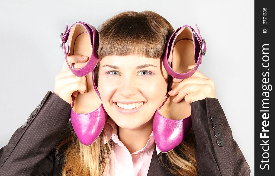 Happy girl with pair of new pink shoes on gray background