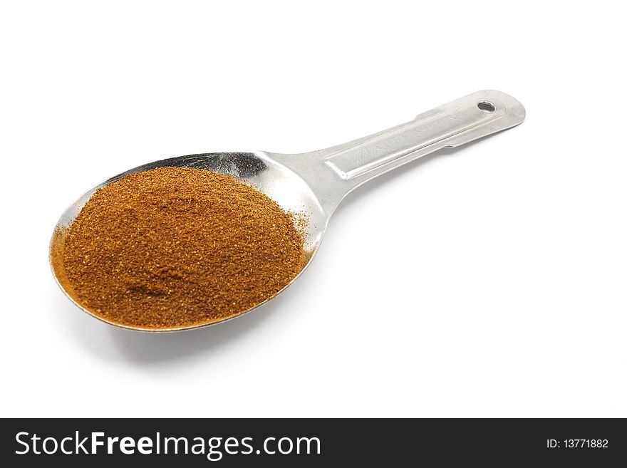 A tablespoon of Paprika in a silver measuring spoon.
