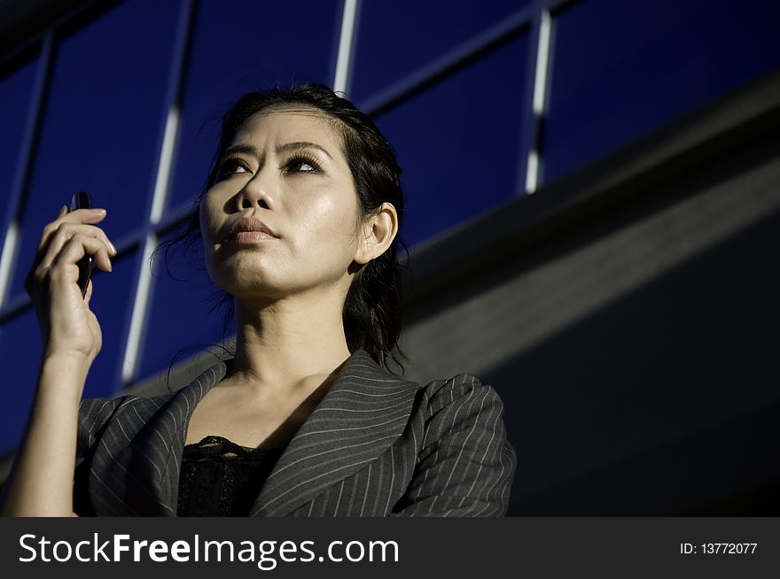 Business woman on the phone with modern office building in background.