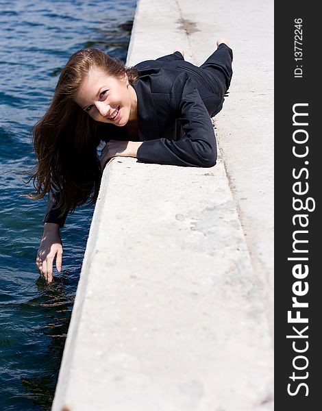 Woman in black suit lying on the border near the water. Woman in black suit lying on the border near the water