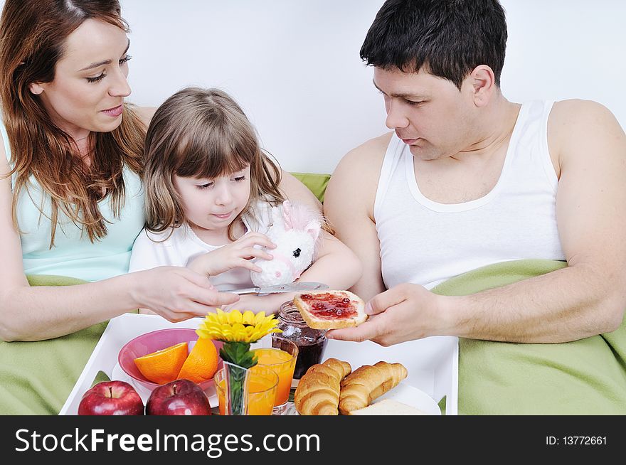 Happy young family eat breakfast in bed at morning