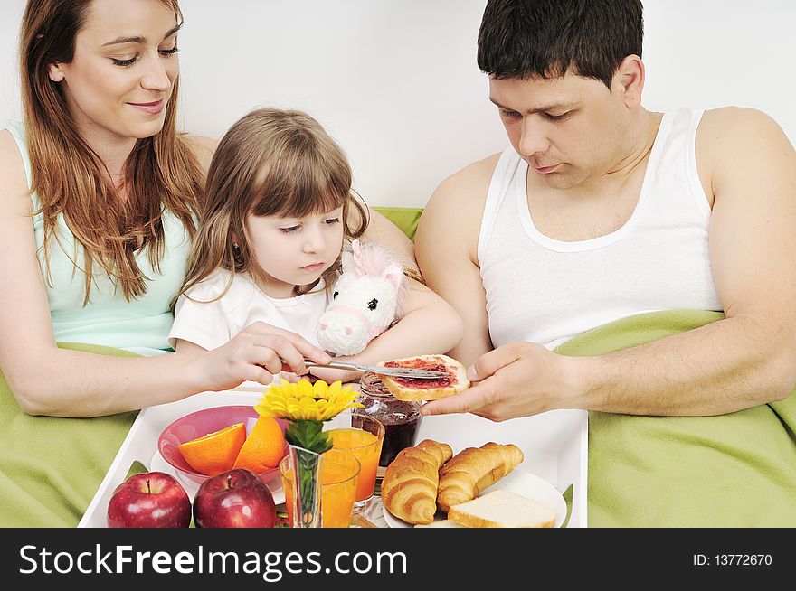 Happy Young Family Eat Breakfast In Bed