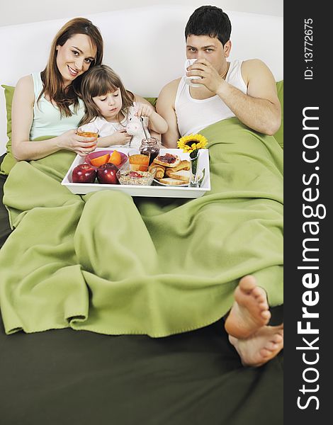 Happy young family eat breakfast in bed