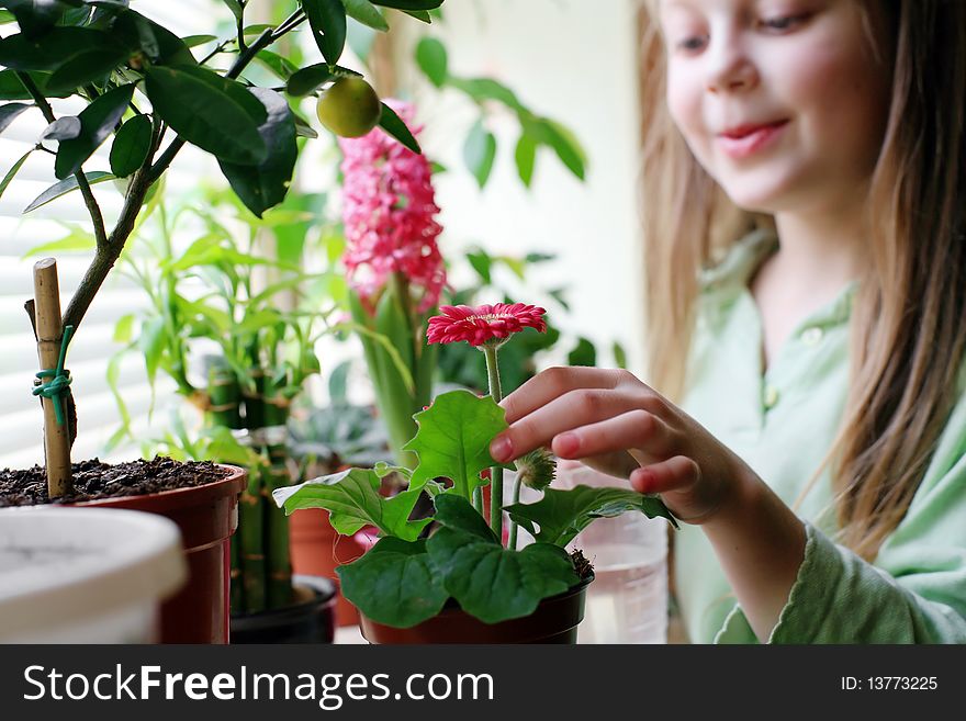 An image of a happy girl watering her flowers