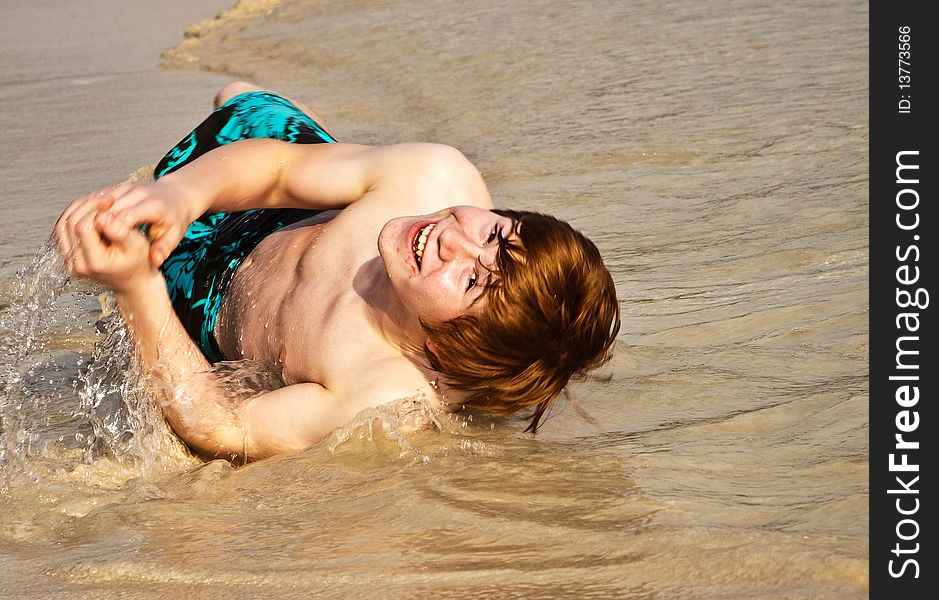 Happy boy with red hair is enjoying the beach