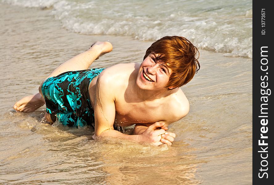 Happy boy is lying at the beach and enjoying