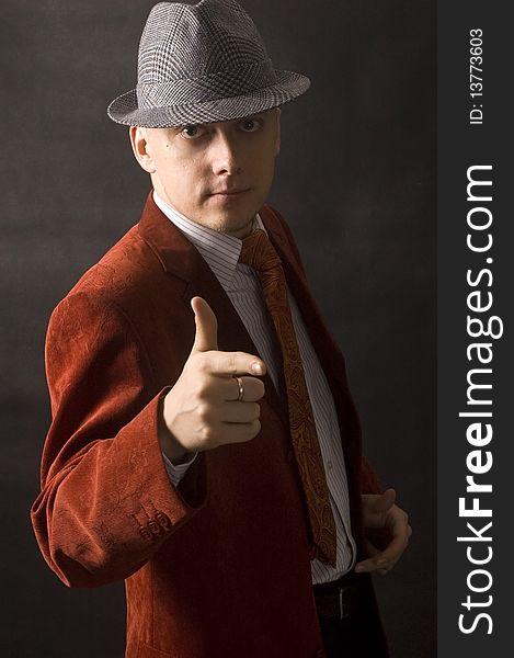 Handsome, young man with hand gesture. Wearing hat, red suit, shirt and red necktie. Serious and calm face expression. Handsome, young man with hand gesture. Wearing hat, red suit, shirt and red necktie. Serious and calm face expression.