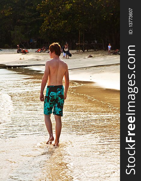 Young boy is walking along the beautiful beach in backlight. Young boy is walking along the beautiful beach in backlight