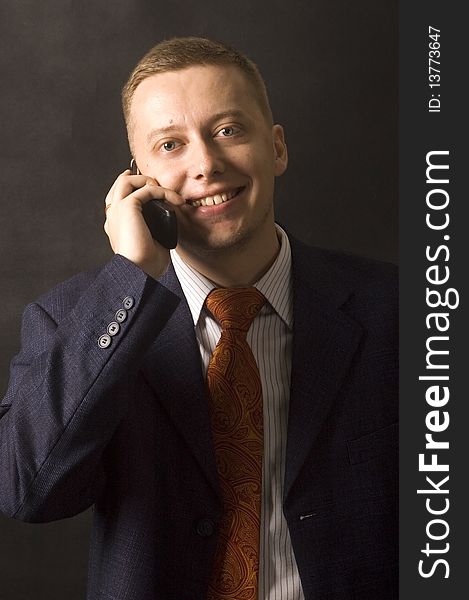 Happy, young and handsome businessman using mobile phone. Wearing tie and suit. Black background. Happy, young and handsome businessman using mobile phone. Wearing tie and suit. Black background.