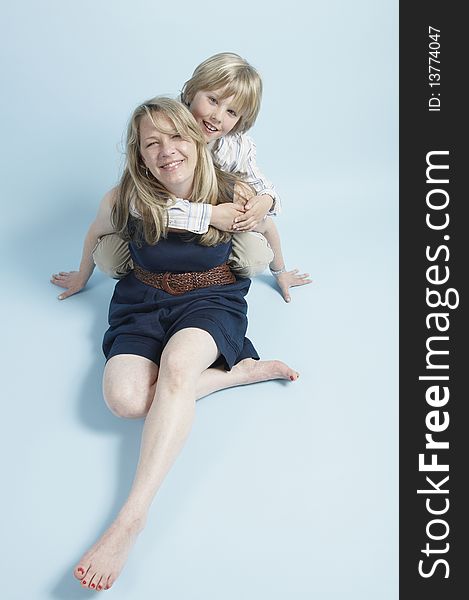 Blond blue eyed born hugging his mom who is seated on the floor. Blond blue eyed born hugging his mom who is seated on the floor