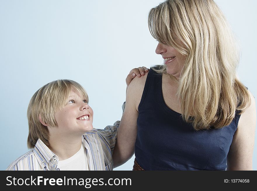 A young boy looks up to his mother with his hand placed on her shoulder. A young boy looks up to his mother with his hand placed on her shoulder