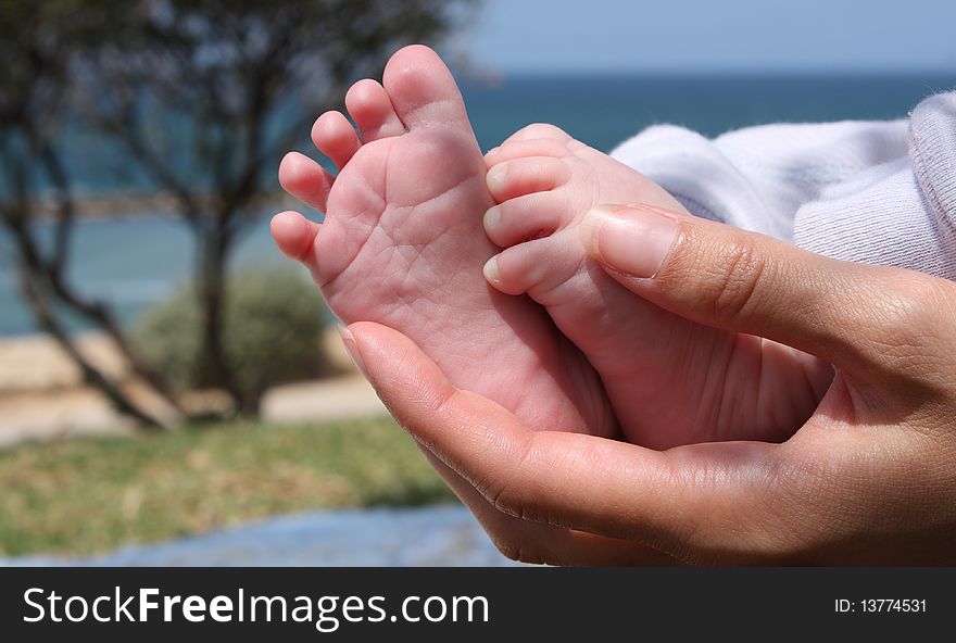 Mom is holding little feet of her son. Mom is holding little feet of her son