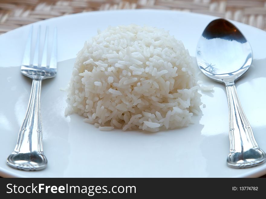 Rice on white dish with spoon and fork.