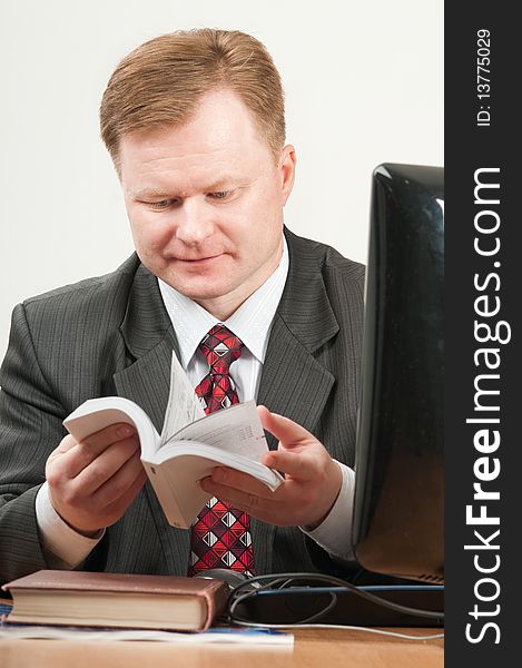 The man of forty five years in a grey suit and a red tie works on the computer. The man of forty five years in a grey suit and a red tie works on the computer.