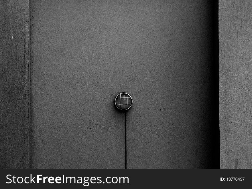 A solitary lamp on a gray wall. A solitary lamp on a gray wall.