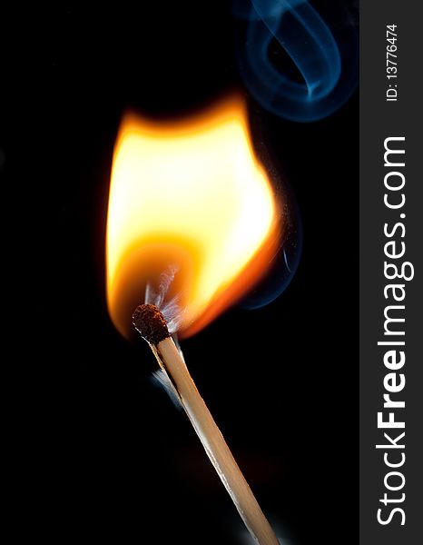 Burning match over black background