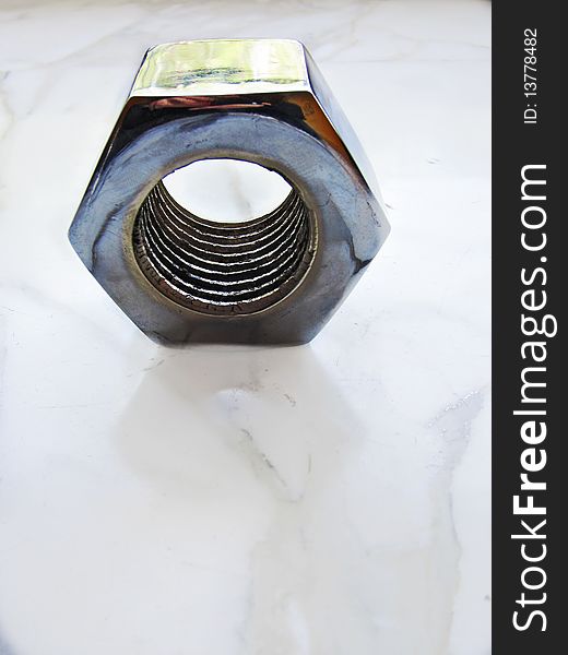 Detail of a metal nut on a marble background. Detail of a metal nut on a marble background