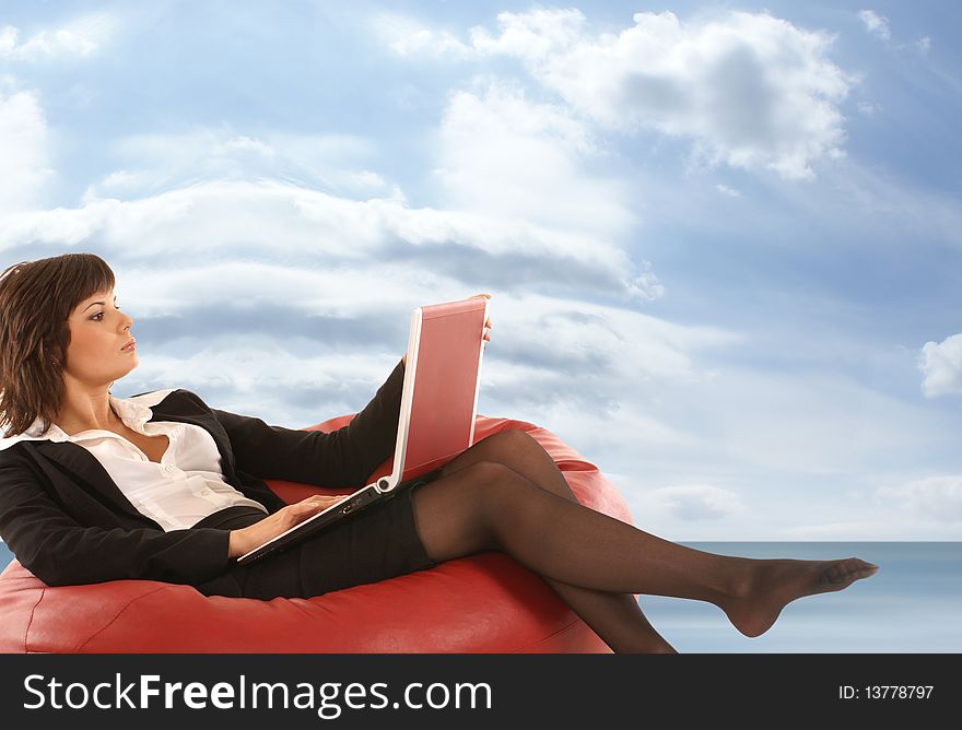 Attractive businesswoman lying on a red sofa holding a notebook. Image taken on a dreamy background with sky and sea. Attractive businesswoman lying on a red sofa holding a notebook. Image taken on a dreamy background with sky and sea.