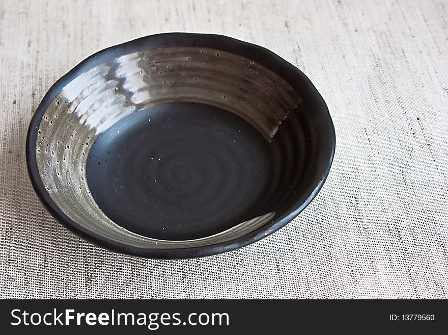 Ceramic black bowl on fabric background