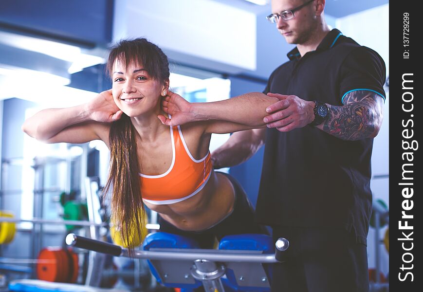 Beautiful woman at the gym exercising with her trainer . Beautiful woman.