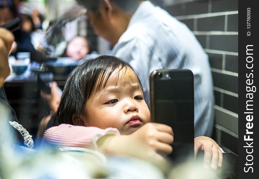 Little kid is playing with mobile phone.