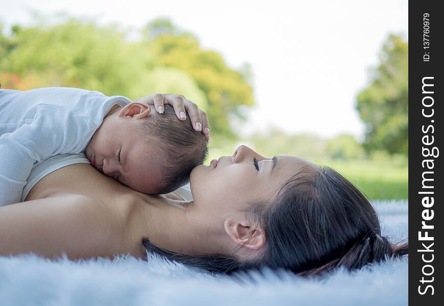 Beautiful mother and her son baby sleeping together in the park, Healthcare and medical love.