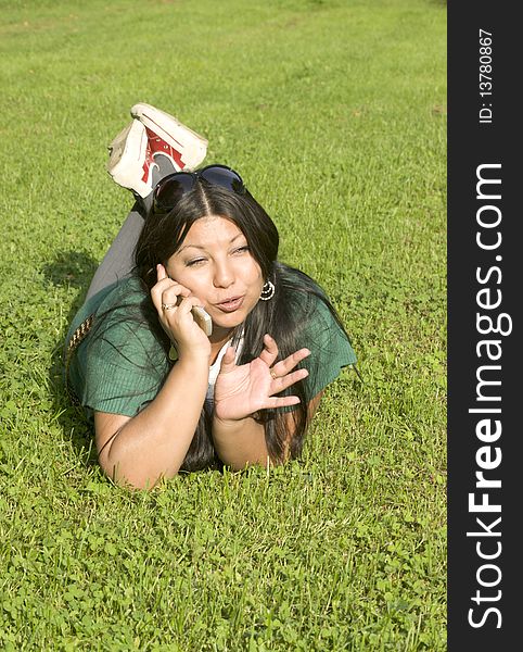 Beauty young woman lies on lawn and speaks by phone. Beauty young woman lies on lawn and speaks by phone