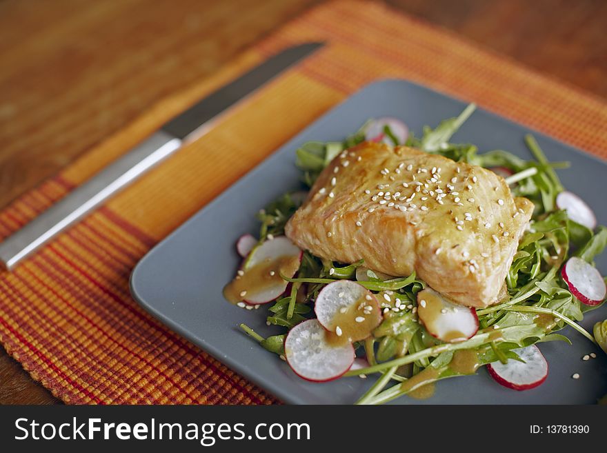 Salmon fillet on rocket salad with sliced radishes and vinaigrette.